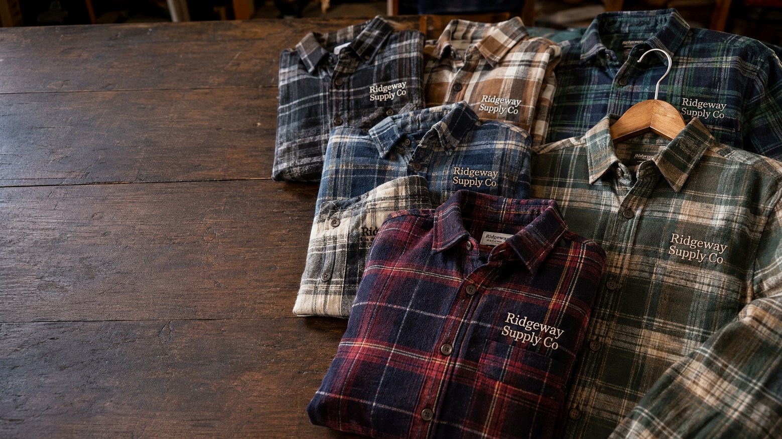 Custom embroidered flannel shirts folded in a stack on a workbench